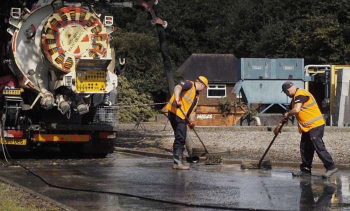 People working next to a vacuum truck tanker